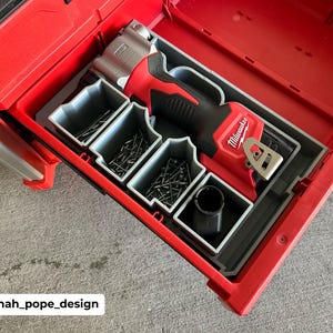 May include: A red Milwaukee tool box with a gray organizer insert. The insert holds a red and silver cordless nail gun and a variety of nails.