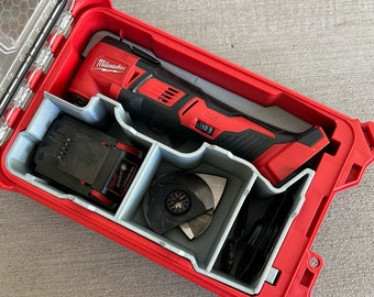Puede incluir: Un kit de herramientas eléctricas Milwaukee rojo con una multiherramienta negra y roja, batería y cuchillas. El kit está organizado en una caja roja con compartimentos grises. La caja está abierta, revelando las herramientas.
