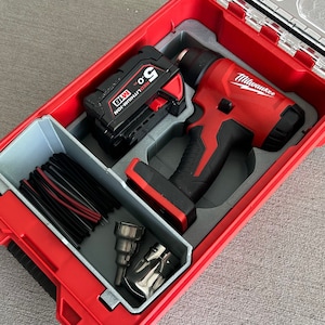 May include: A red and black cordless heat gun with a Milwaukee logo, a black battery, and a variety of attachments in a red and gray hard case.