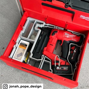 May include: A red Milwaukee FUEL 2.0 cordless brad nailer with a gray and black plastic storage case. The nailer is in a red toolbox with a gray foam insert. The nailer has a 5.0 Ah REDLITHIUM-ION M18 battery.