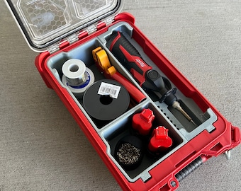 May include: A red toolbox with a clear lid, containing soldering tools. Includes a soldering iron, solder, wire, and two red batteries. The interior is gray with compartments to organize the tools.