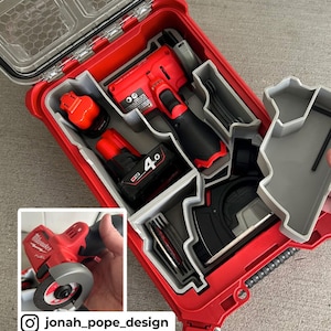 May include: A red tool box with a gray interior and multiple compartments. The box contains a variety of power tools, including a red and black cordless drill, a red and black cordless grinder, and a black and gray cordless saw. The box is open and the tools are visible.