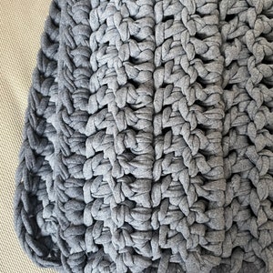 Puede incluir: Una manta de crochet gris con un patr&oacute;n texturizado. La manta est&aacute; hecha de hilo grueso y tiene una sensaci&oacute;n suave y acogedora.