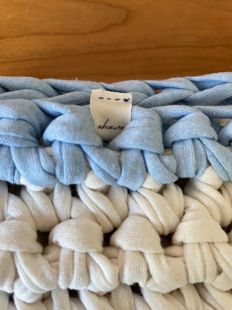Puede incluir: Primer plano de una manta de crochet azul y blanca con una etiqueta blanca que dice "ahaia".