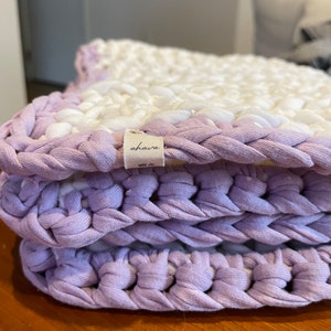 Puede incluir: Un primer plano de una alfombra de crochet de color morado y blanco con una etiqueta que dice "ahava".