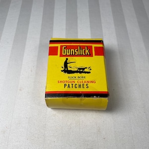 Peut inclure: Une boîte jaune de tampons de nettoyage pour fusil de chasse Gunslick. La boîte a une bordure noire et rouge avec le logo Gunslick et une silhouette d'une personne tirant avec un fusil de chasse. Le texte "Slick Bore Shotgun Cleaning Patches" est imprimé.