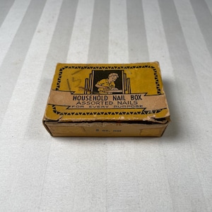 May include: A vintage yellow and brown cardboard box labeled "HOUSEHOLD NAIL BOX ASSORTED NAILS FOR EVERY PURPOSE." The box features a graphic of a person and contains 5 oz. of nails.