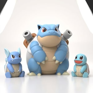 May include: A set of three blue and tan plastic character figurines. The central figure is a large, bipedal creature with two cannons on its back. To the left is a smaller, seated creature with pointed ears, and to the right is a small, smiling creature.