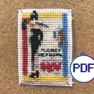 May include: Cross-stitch pattern of a cartoon character wearing a black suit and hat, with the text "MURDER SHE WROTE" and a red "W" in the background.