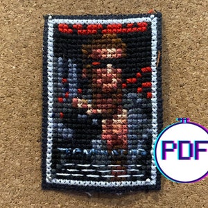 May include: A rectangular, cross-stitched patch featuring a figure with red accents against a dark background. The patch has a white border and the word "Tomb" is visible. A circular logo with the letters "PDF" is in the lower right corner.