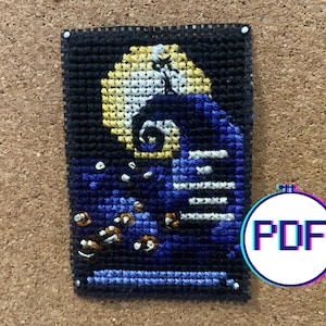 May include: Cross stitch pattern of Jack Skellington from The Nightmare Before Christmas, standing on a hill with a full moon behind him. The pattern is in black, white, blue, and yellow thread.