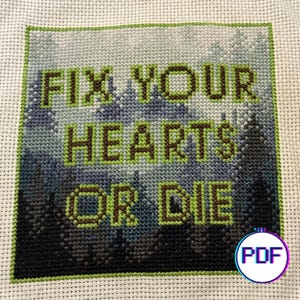 Könnte beinhalten: Kreuzstichmuster mit grünem, blauem und schwarzem Hintergrund. Der Text "Fix your hearts or die" ist in braunem und grünem Garn gestickt.