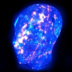 Peut inclure: Une sculpture en verre bleue et violette d'une tête humaine avec une surface texturée.