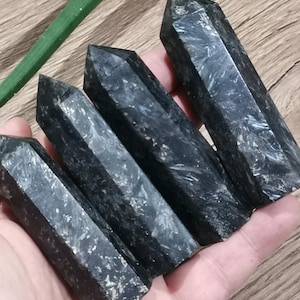 May include: Four black obsidian crystal points with a silvery shimmer. The points are arranged in a row, with the largest point at the top and the smallest point at the bottom.
