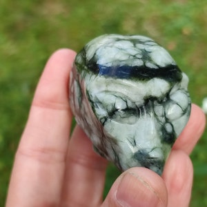 Peut inclure: Un crâne en pierre sculpté de couleur verte et blanche avec des détails complexes. Le crâne a un visage avec des yeux, un nez et une bouche.