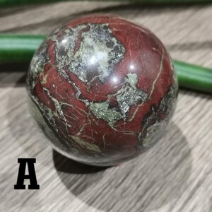 Peut inclure: Une sphère rouge, verte et noire avec un motif marbré. La sphère est en pierre polie.