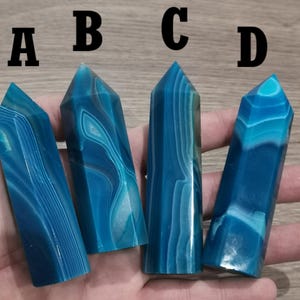 Peut inclure: Quatre pointes de cristal d'agate bleue avec des bandes blanches. Les pointes sont disposées en rangée de gauche à droite, étiquetées A, B, C et D.