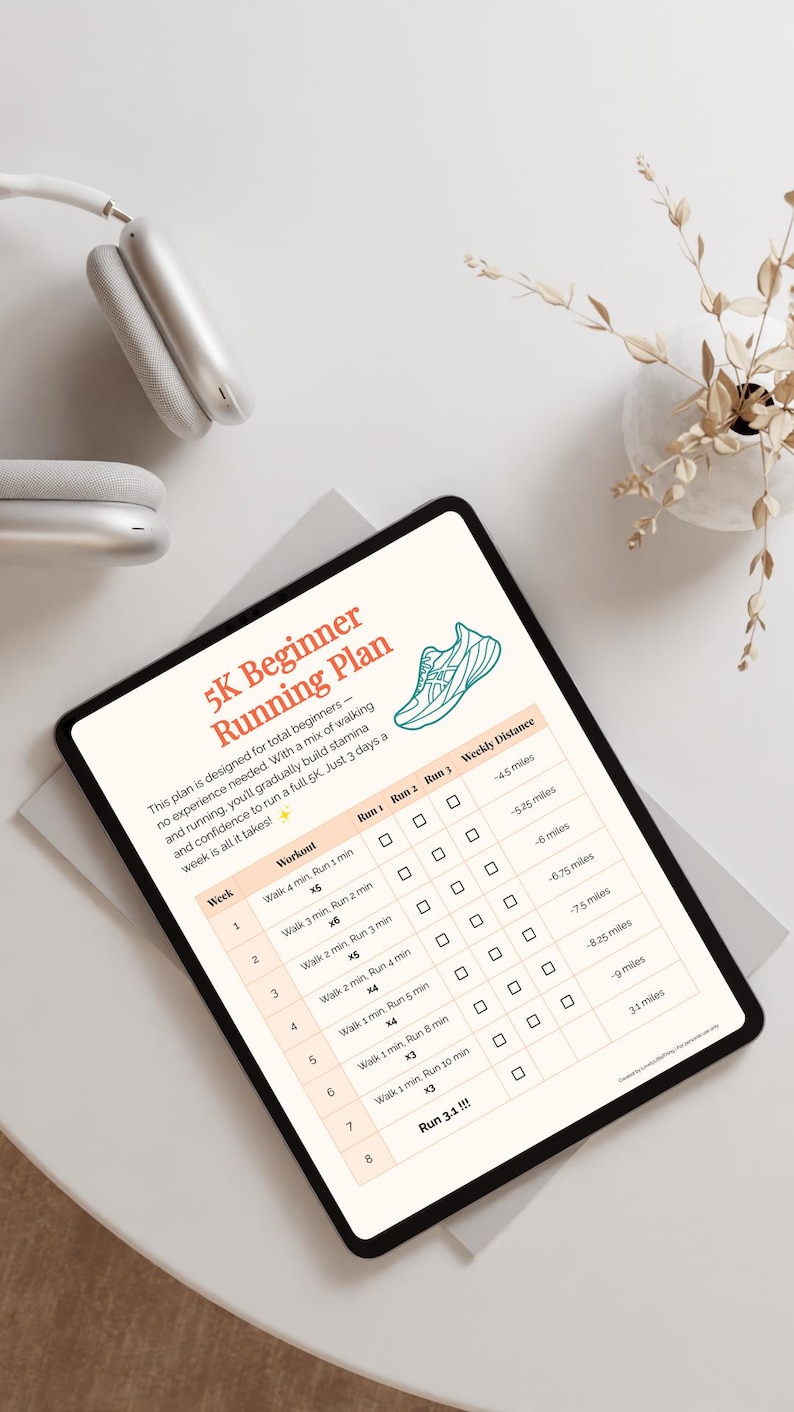May include: A digital tablet displays a 5K Beginner Running Plan with a running shoe graphic. The plan includes a weekly workout schedule with run and walk intervals, and weekly distance goals. A pair of white headphones and a small vase with dried plants are also visible.