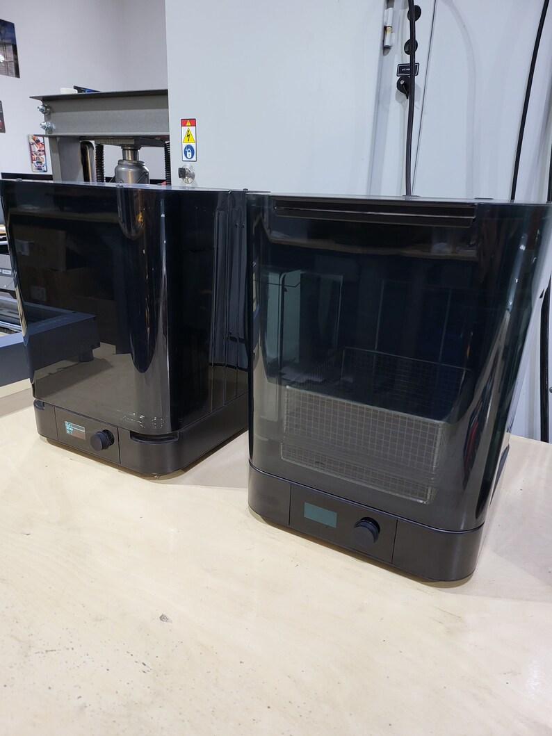 May include: Two black, rectangular, countertop appliances with a clear, glass door. The appliance on the left has a control panel with a knob. The appliance on the right has a control panel with a knob and a digital display.