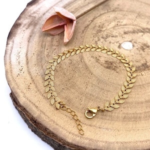 May include: A gold leaf chain bracelet with a lobster clasp closure. The bracelet is made of metal and has a delicate, feminine design.