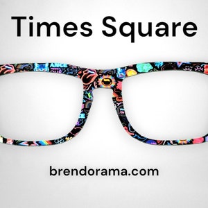 Peut inclure: Lunettes à monture noire avec un motif coloré d'autocollants et de texte, notamment "Times Square" et "brendorama.com".