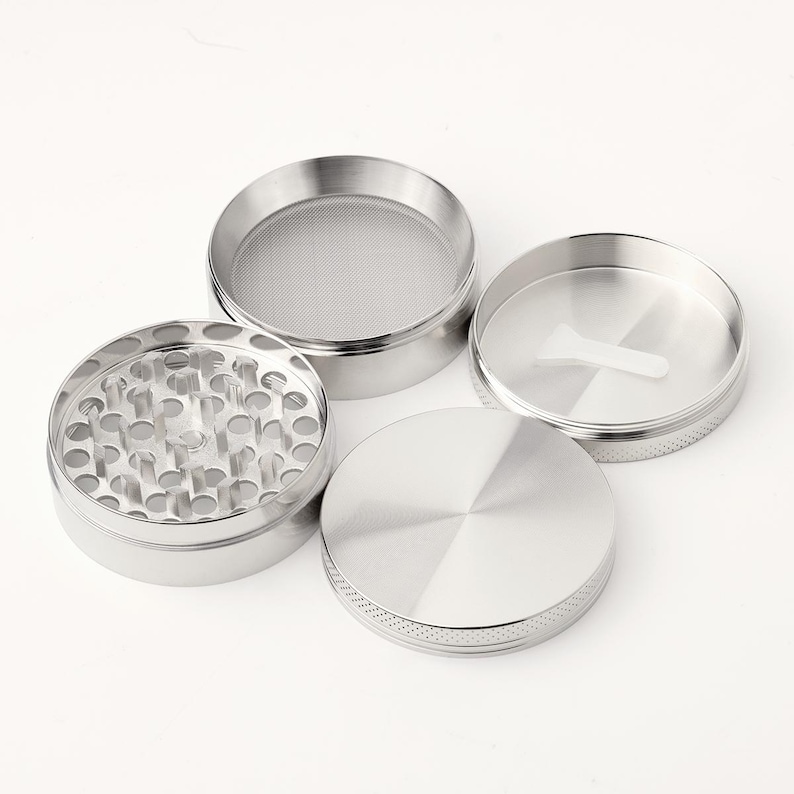 May include: A four-piece silver metal grinder with a screen, a top, a bottom, and a middle section with teeth.