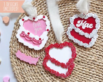 Può includere: Tre ornamenti a forma di cuore tagliati al laser con sfondo bianco e disegni rossi e bianchi. Gli ornamenti presentano il testo "love you", "Mae" e uno spazio vuoto per la personalizzazione.
