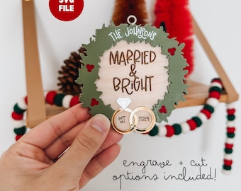 May include: A green wreath ornament with the text "The Johnsons Married & Bright" and the year "2024" engraved on it. The ornament also features two gold rings with a diamond.