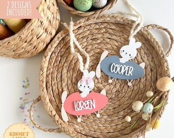 Puede incluir: Dos etiquetas con temática de avión de Pascua con un conejito, con los nombres "Cooper" y "Loreen" escritos en ellas. Las etiquetas son de papel y están decoradas con pintura rosa y azul. Las etiquetas están sobre una cesta tejida.