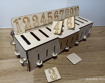 May include: Wooden number holder with a numbered track on top and slots for numbered tiles. The tiles are numbered 3, 4, and 6. The track is numbered 1 through 10.