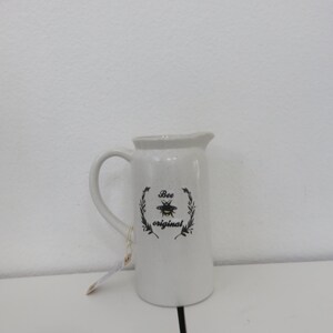 May include: White ceramic jug with a black and yellow bee design and the text "Bee original".