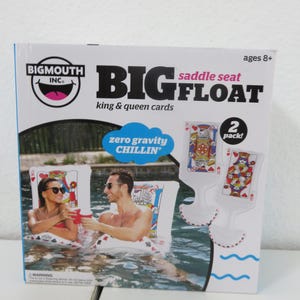 Pode incluir: Um pacote de 2 assentos flutuantes BigMouth Inc. Big Float com designs de cartas de rei e rainha. A embalagem exibe o texto 'zero gravity CHILLIN'' e mostra dois assentos infláveis para piscina com gráficos de cartas em vermelho, preto e branco.