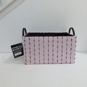 Puede incluir: Cesta de almacenamiento rosa y negra con asas negras y el texto "STORAGE BASKET" en una etiqueta blanca.