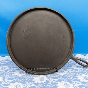 May include: A cast iron skillet with a black finish and a handle. The skillet has the words "Favorite Stove & Range Co." embossed on the bottom. The skillet is 10 inches in diameter.