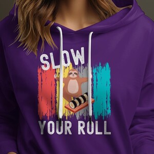 May include: Purple hoodie with a white graphic of a sloth holding a sushi roll. The graphic says "Slow Your Roll".