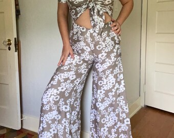 May include: A brown and white floral print jumpsuit with a tie-front top and wide-leg pants.