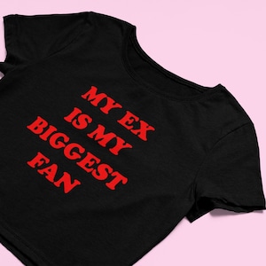 May include: Black cropped t-shirt with red text that reads "My ex is my biggest fan".