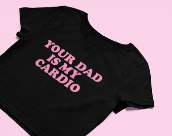 Puede incluir: Top corto negro con texto rosa que dice "Your Dad Is My Cardio".