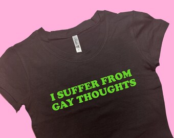 Puede incluir: Camiseta negra de corte corto con el texto "I suffer from gay thoughts" en verde.