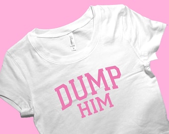 Puede incluir: Top corto blanco con el texto "DUMP HIM" en letras rosas. La camiseta tiene cuello redondo y mangas cortas. El fondo es de color rosa liso.