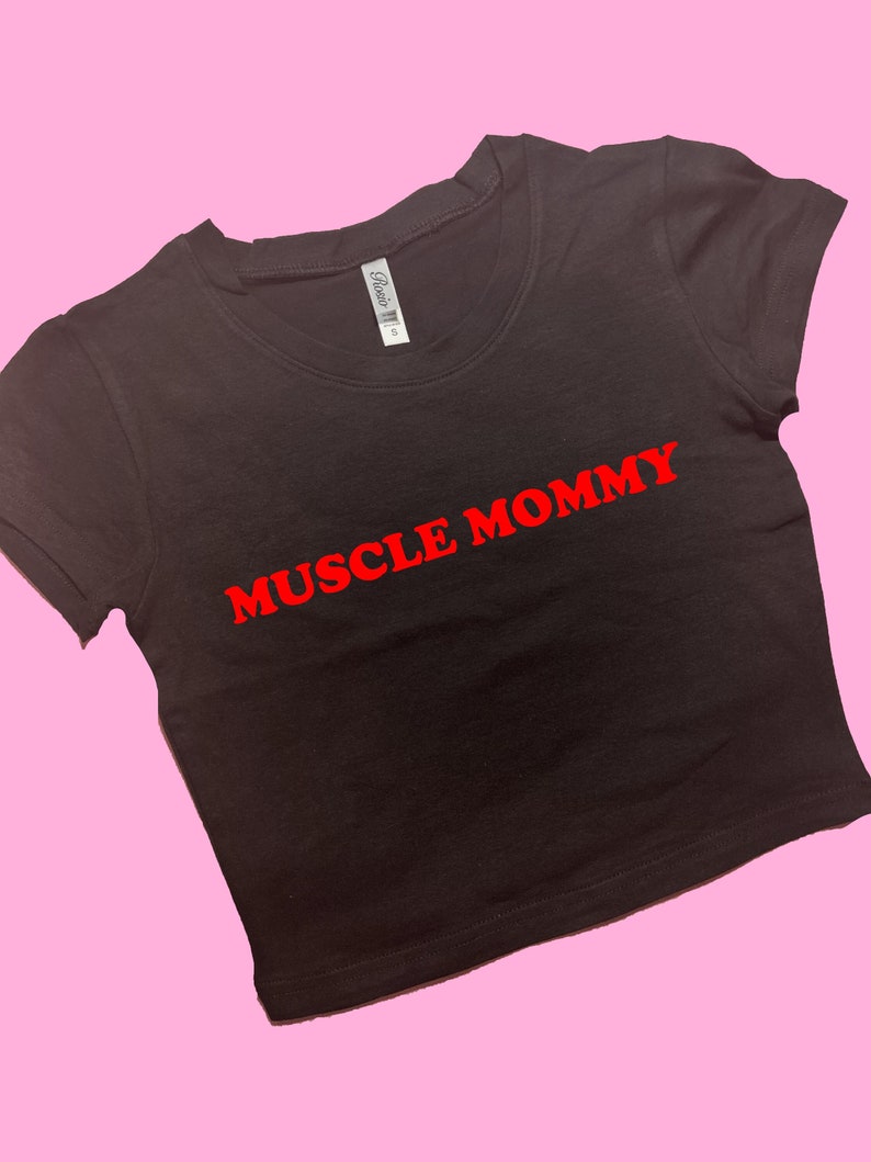 May include: Black cropped t-shirt with red text that says "MUSCLE MOMMY"