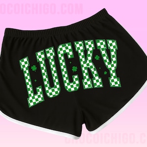 May include: Black shorts with white trim and the word "LUCKY" in large, green and white checkered letters. The word "LUCKY" has three green shamrocks. The shorts have an elastic waistband.
