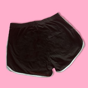 May include: Black athletic shorts with a white trim around the edges. The shorts are made of a soft, comfortable fabric.