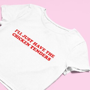 May include: White cropped t-shirt with red text that reads "I'll just have the chicken tenders".
