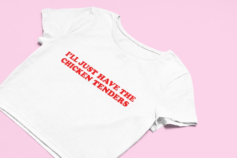 May include: White cropped t-shirt with red text that reads "I'll just have the chicken tenders".