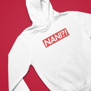 K&ouml;nnte beinhalten: Wei&szlig;er Kapuzenpullover mit Fronttasche und Kordelzug. Der rote rechteckige Aufdruck auf der Brust zeigt "NANI?!" in wei&szlig;en Gro&szlig;buchstaben. Der Hintergrund ist einfarbig rot.