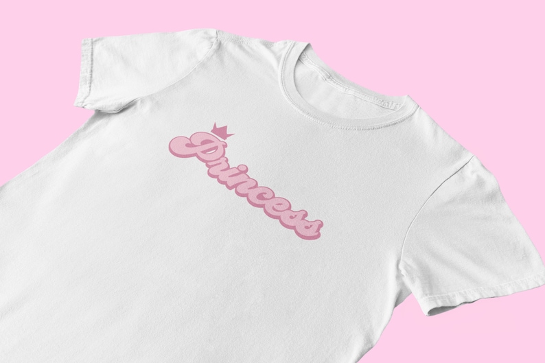 May include: White t-shirt with a pink "Princess" graphic with a crown above the word.