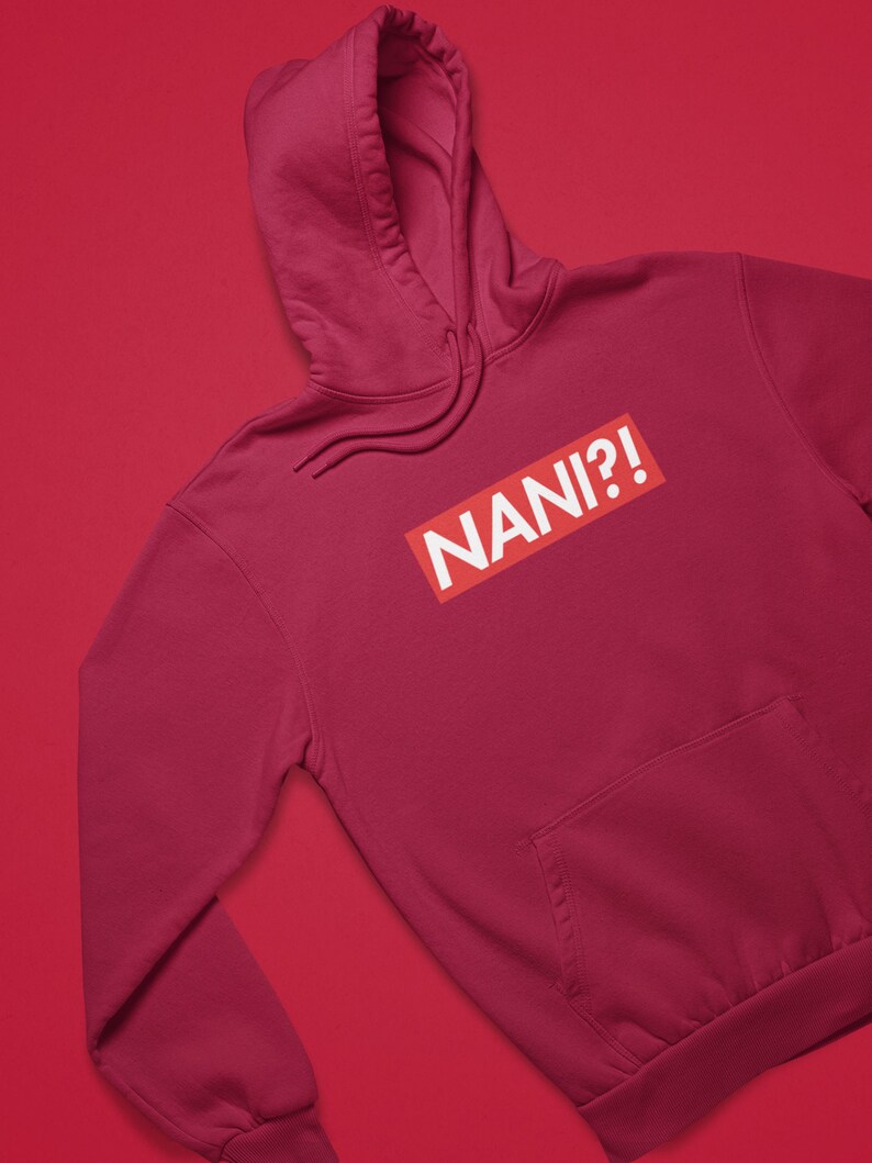 K&ouml;nnte beinhalten: Ein weinroter Kapuzenpullover mit einer Vordertasche und einer Kapuze. Der Kapuzenpullover zeigt das Wort "NANI?!" in wei&szlig;em Text in einem roten Rechteck.