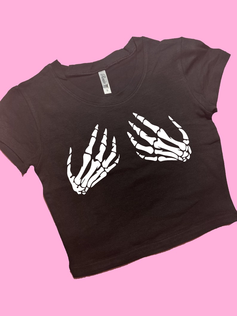 May include: Black cropped t-shirt with a white skeleton hand graphic on the front.