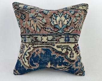 May include: A decorative throw pillow with a blue, pink, and white floral pattern. The pillow is made from a woven fabric and has a fringed edge.